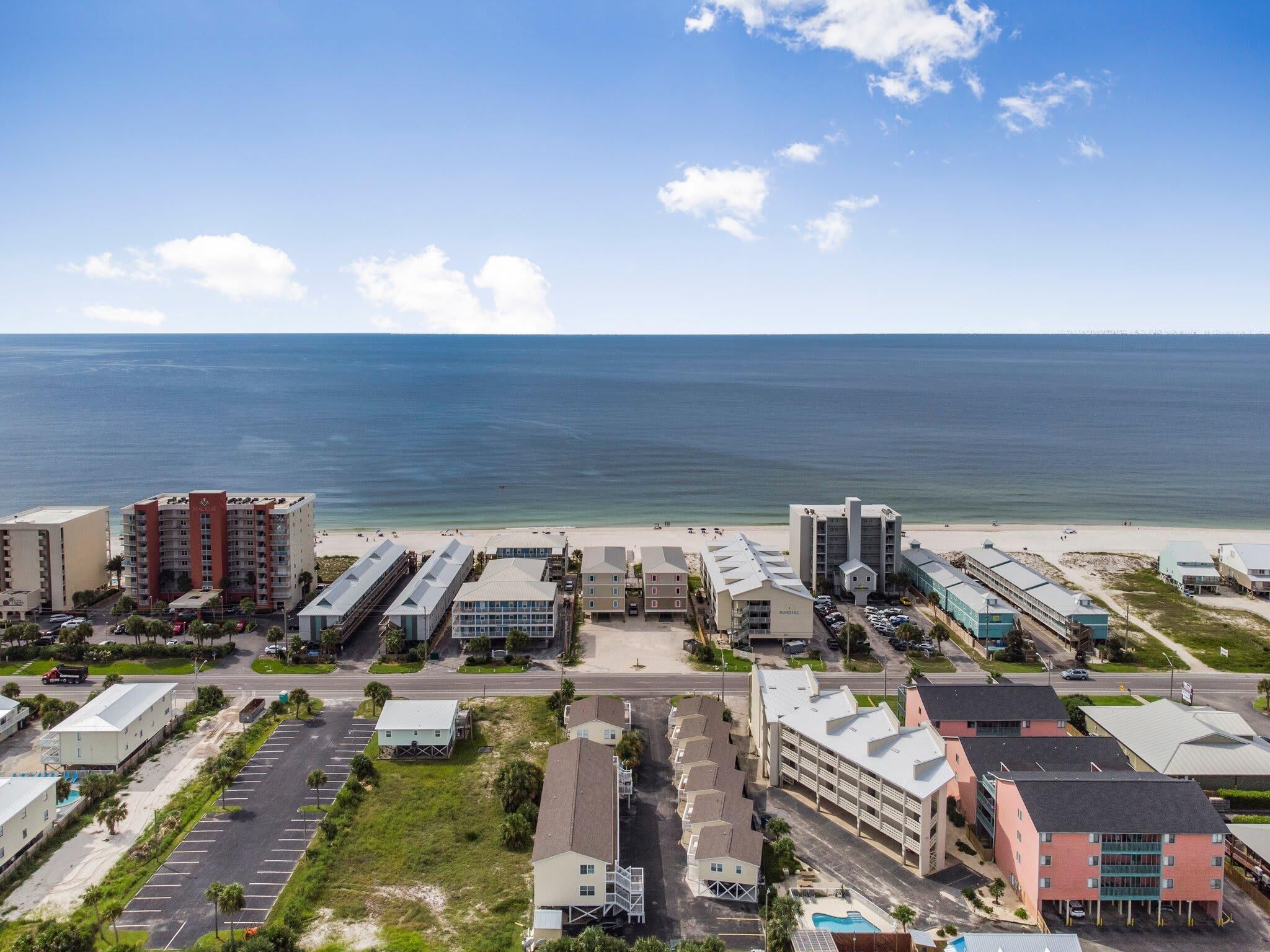 Ein Hotelkomplex direkt an der Küste mit mehreren Gebäuden, einem Parkplatz und Blick auf den Strand.