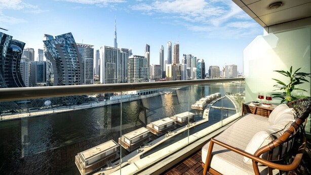 A balcony with a view of a city skyline, including modern buildings and a river. - Waterfront Escape | Burj & Canal View | Pool+Sauna (Dubai)