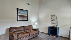 Uma sala de estar com um sofá de couro marrom, um rack azul e um quadro na parede.