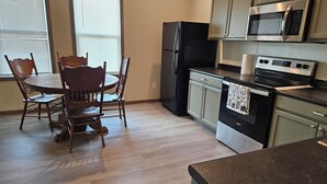 Uma cozinha com mesa e cadeiras, geladeira, micro-ondas e forno.