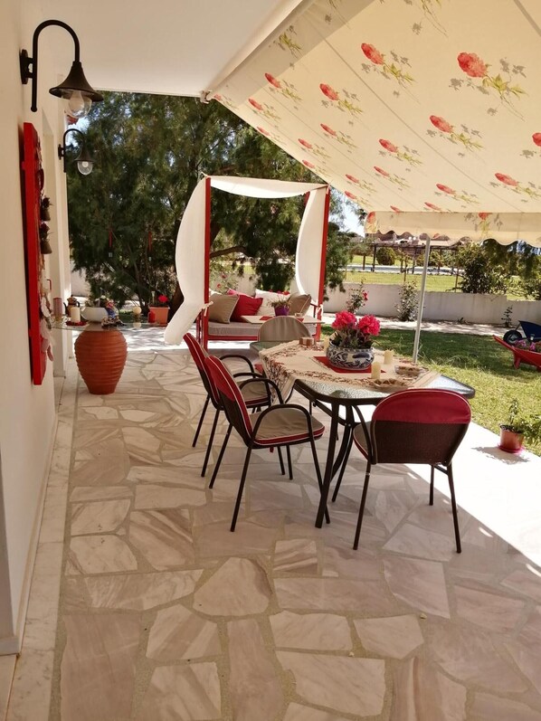 Eine Außenpatio mit Steinböden, einer überdachten Sitzgruppe und einem Tisch mit Stühlen.