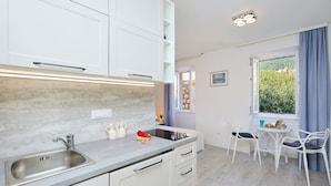 A modern kitchen with a sink, cabinets, and a dining area with chairs and a table. - Sophie 1 - Old Town Heritage Suite (Dubrovnik)