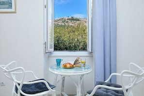 A room with a view of a hill, a table with a book, a glass of juice, and two chairs. - Sophie 1 - Old Town Heritage Suite (Dubrovnik)