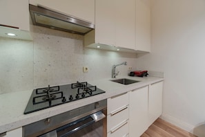 Une cuisine moderne équipée d’une cuisinière à gaz, d’un évier en acier inoxydable et de meubles blancs.