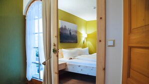 Een slaapkamer met een bed, een wandlamp en een raam met gordijnen.