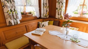 Een houten tafel met een boek, brillen, een kantbeschermer, een vaas met een roos en een glas water.