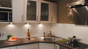 Een moderne keuken met roestvrijstalen apparatuur, een spoelbak en een aanrecht met een bord groenten en een fles.