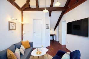 Ein Wohnzimmer mit einer Couch, einem Couchtisch und einem an der Wand befestigten Fernseher.