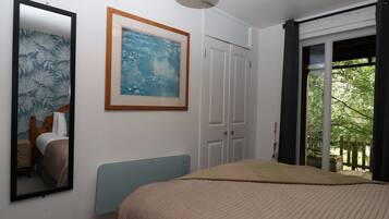 Ein Schlafzimmer mit einem Bett, einem gerahmten Gemälde, einem Spiegel und einer Tür, die auf einen Balkon führt.