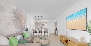 A modern living room with a sofa, coffee table, and a painting of a beach. - Stunning 1BR Apartment with Balcony & Pool (Hallandale Beach)