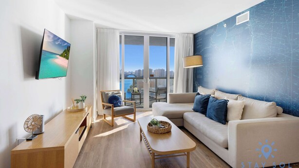 A modern living room with a sofa, coffee table, and a TV mounted on the wall. - Bright Apartment | Panoramic View | Resort Vibe (Hallandale Beach)
