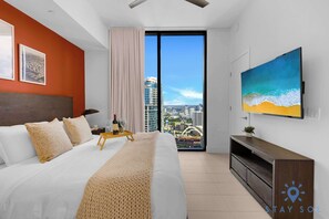 Ein modernes Hotelzimmer mit einem großen Bett, einem Fernseher und Blick auf die Stadt.