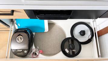 A drawer containing a digital scale, a blue notebook, a round mat, and two circular objects.