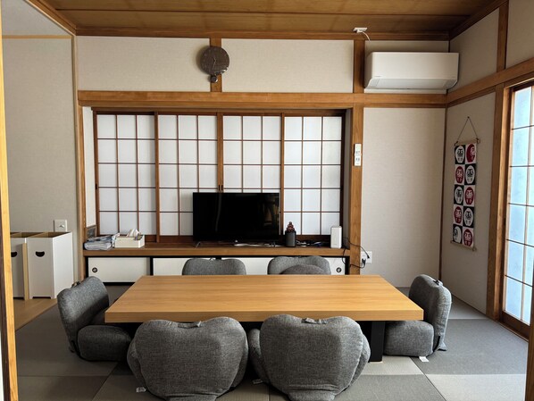 A traditional Japanese-style room with tatami flooring, a low wooden table, and a television set.