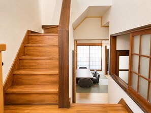 A wooden staircase leading to a room with tatami mats, a low table, and a sofa.