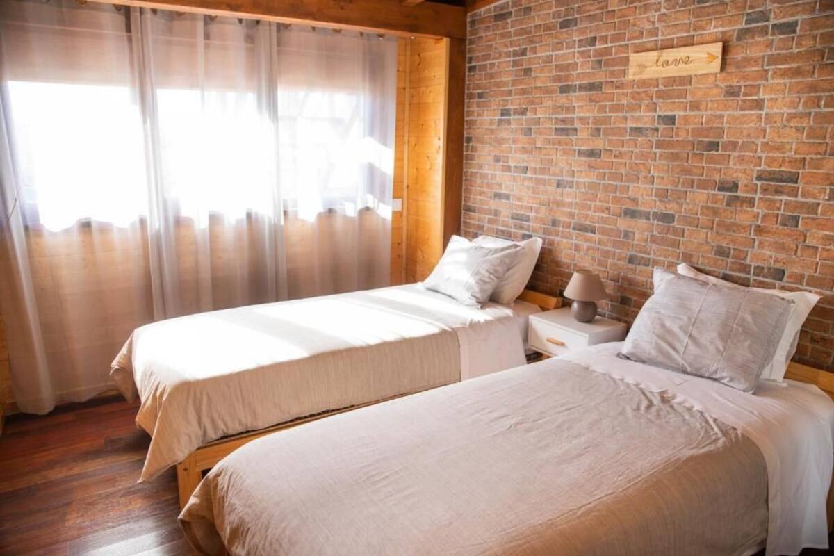 Ein Zimmer mit zwei Betten, Holzböden, einer Backsteinwand und einem Schild mit der Aufschrift 'love'.