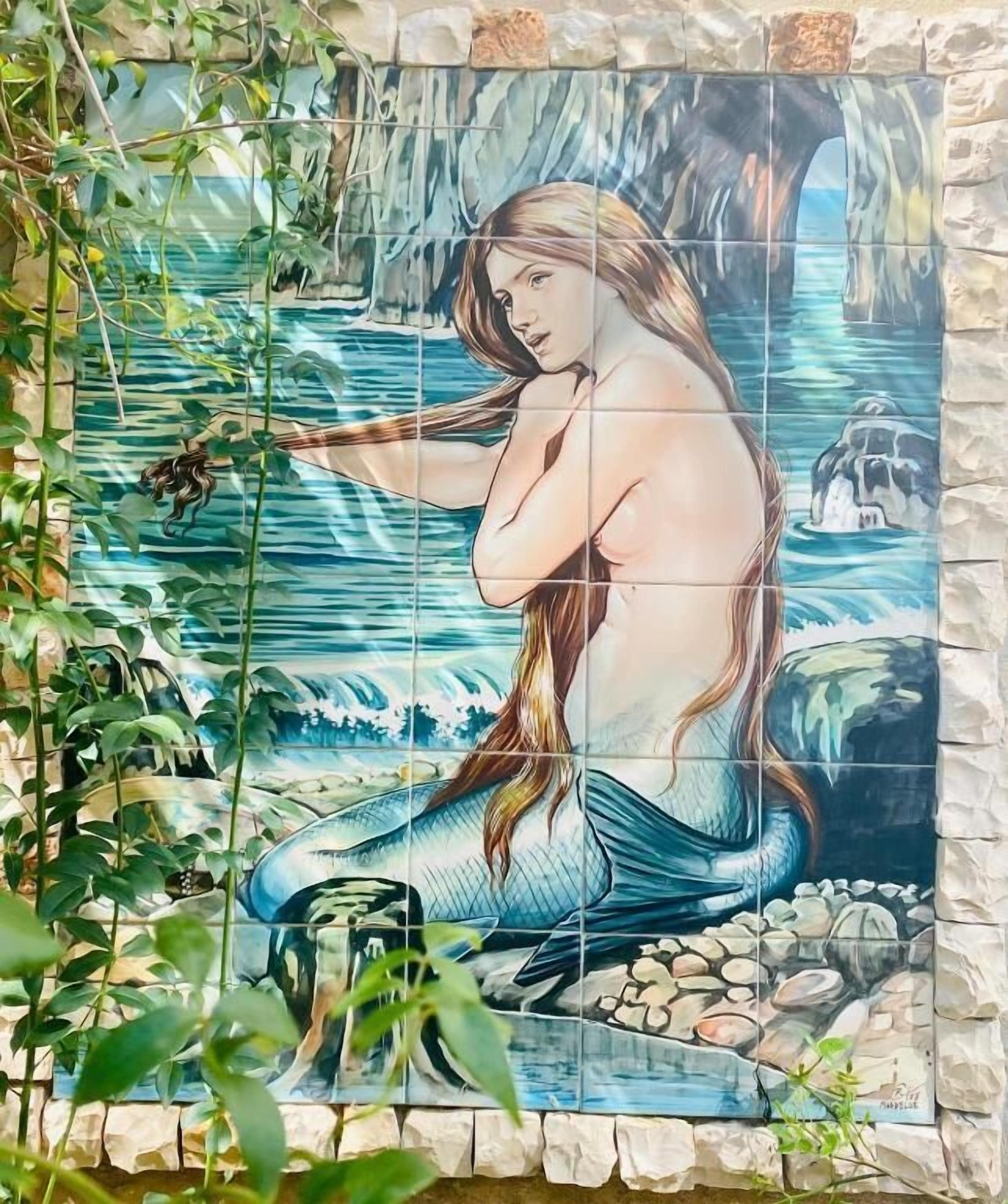 Un mosaico de una sirena frente a un fondo rocoso.