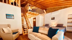 A cozy living room with a wooden staircase, a sofa set, and a small table. - AlvorKiteCenter Guesthouse (Portimao)