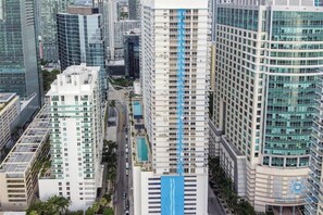 A high-rise building with a prominent blue swimming pool, surrounded by other tall buildings. - Comfortable Apartment with pool (Miami)