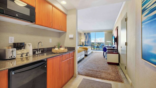 A compact kitchen with wooden cabinets, a built-in microwave, and a dishwasher. - Cozy Studio Balcony & Access to Sandy Beach (Sunny Isles Beach)