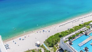 An aerial view of a beach with a pool area, including a swimming pool, umbrellas, and lounge chairs. - Bright & Spacious 2BR w/Balcony (Hollywood)