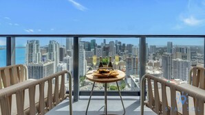 A high-rise room with a city view, a small round table with a bottle and a glass, and two chairs. - 1BR Apartment with Pool and gym (Miami)