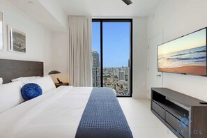 A modern hotel room with a large bed, a TV on the wall, and a city view through the window. - City Views Stylish Apartment - 1BR (Miami)