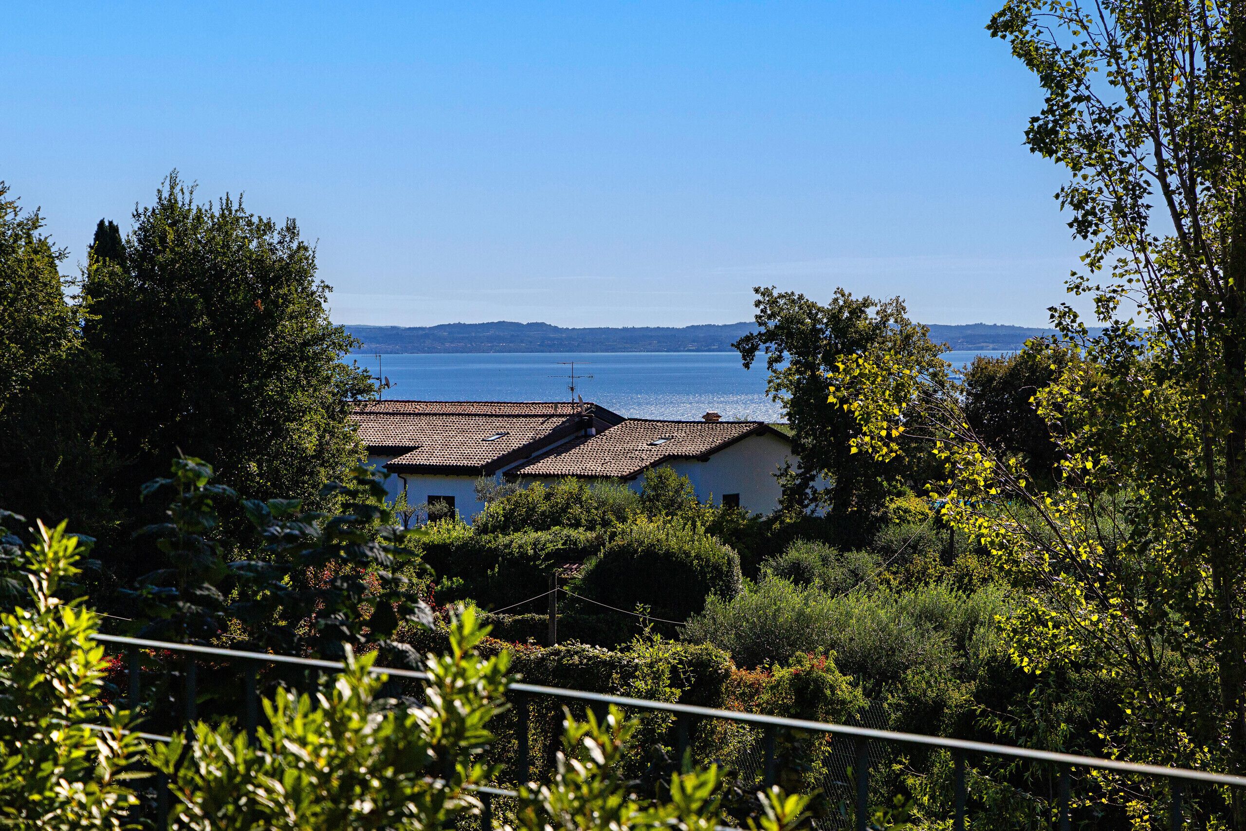 Une maison située sur la côte, avec un toit recouvert de tuiles, entourée d’une végétation luxuriante et offrant une vue sur la mer.