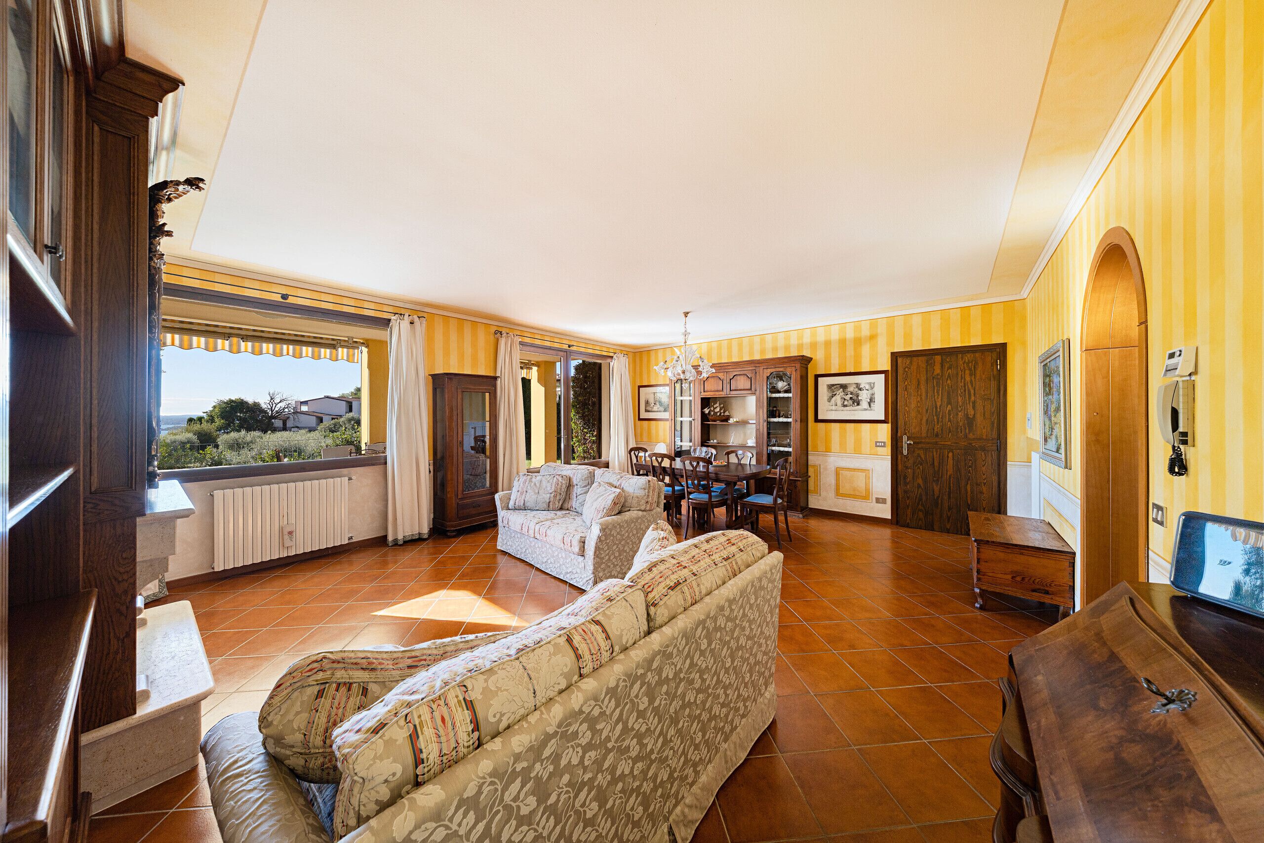 A spacious living room with a sofa, a dining table, and a view of the outdoors.