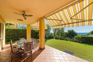 An outdoor patio with a table set for dining, a ceiling fan, and a view of the sea. - Large apartment with lake view and swimming pool (Soiano del Lago)