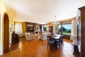 A spacious living area with a dining table, sofas, and a fireplace. - Large apartment with lake view and swimming pool (Soiano del Lago)