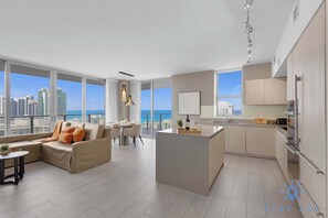 Eine moderne Wohnung mit Essbereich, Sofa, Küche und großen Fenstern mit Blick auf die Stadt.
