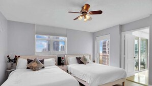 A hotel room with two beds, a ceiling fan, a large window, and a balcony with a view of high-rise buildings. - Amazing Apt w/Ocean View + Pool & Gym (Miami)