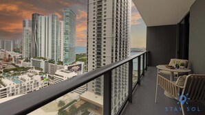 Ein Balkon mit Blick auf hohe Gebäude und ein Gewässer.