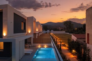 Un edificio moderno con piscina, zona de estar al aire libre y vistas a las montañas.