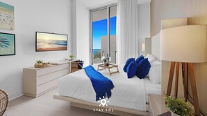 A modern hotel room with a bed, a desk, a chair, a lamp, and a large window with curtains. - Beautiful Apt w/ Amazing Pool and Private Balcony (Hollywood)