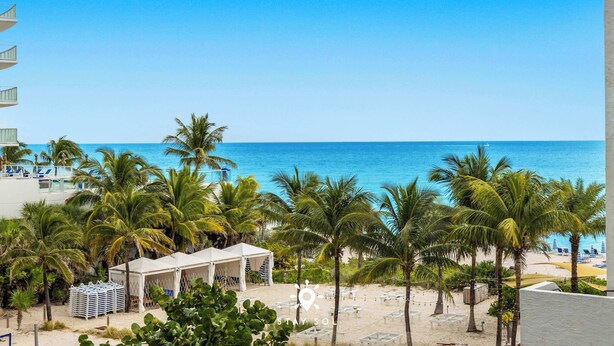 A beach view with palm trees, a pool area, and a beach chair setup. - Beautiful Apt w/ Amazing Pool and Private Balcony (Hollywood)