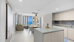 A modern kitchen with a central island, a dining area with a view, and a living space with a sofa and a table. - Ocean Bliss Retreat - 2 BR. Apartment (Hollywood)