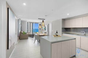 A modern kitchen with a central island, a dining area with a view, and a living space with a sofa and a table. - Ocean Bliss Retreat - 2 BR. Apartment (Hollywood)
