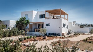 Un edificio moderno de color blanco con terraza de madera y un pequeño jardín.