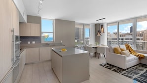 Un apartamento moderno con cocina, comedor y sala de estar. Cuenta con ventanas amplias, un balcón y vistas a la ciudad.
