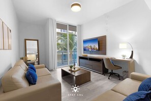 A modern living room with a sofa, coffee table, and desk area. - The Best Stay| Hot Tub & Pool|Hollywood Beach+ Gym (Hollywood)