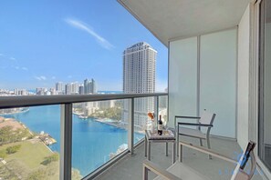 Un balcón con vista despejada a un horizonte urbano y una masa de agua.