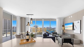 A modern living room with a city view, a dining area with a tray of wine, and a flat-screen TV. - Spectacular View 2BR | Pools & Relax (Hollywood)