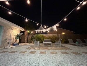 A patio area with string lights, outdoor furniture, and a covered seating area.