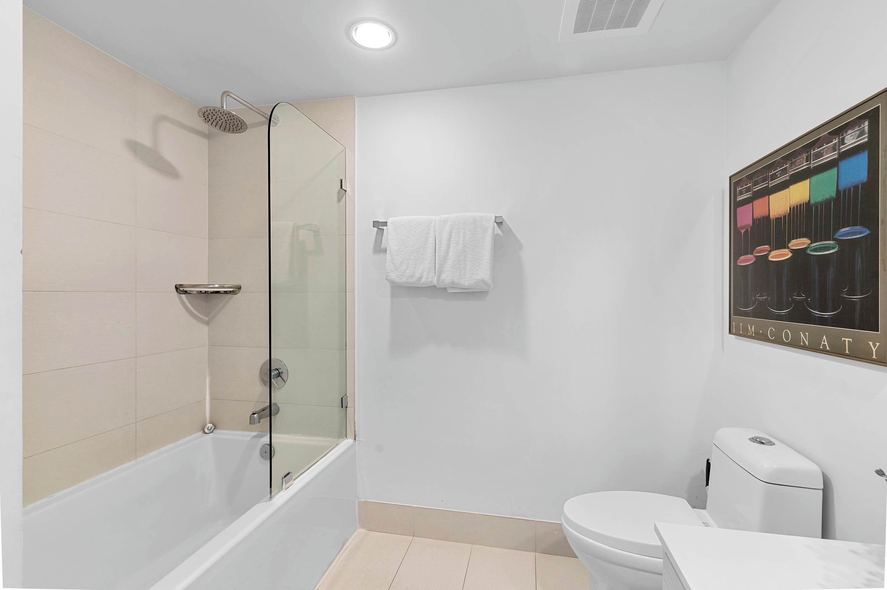 A modern bathroom with a glass-enclosed shower, a white toilet, and a marble sink.