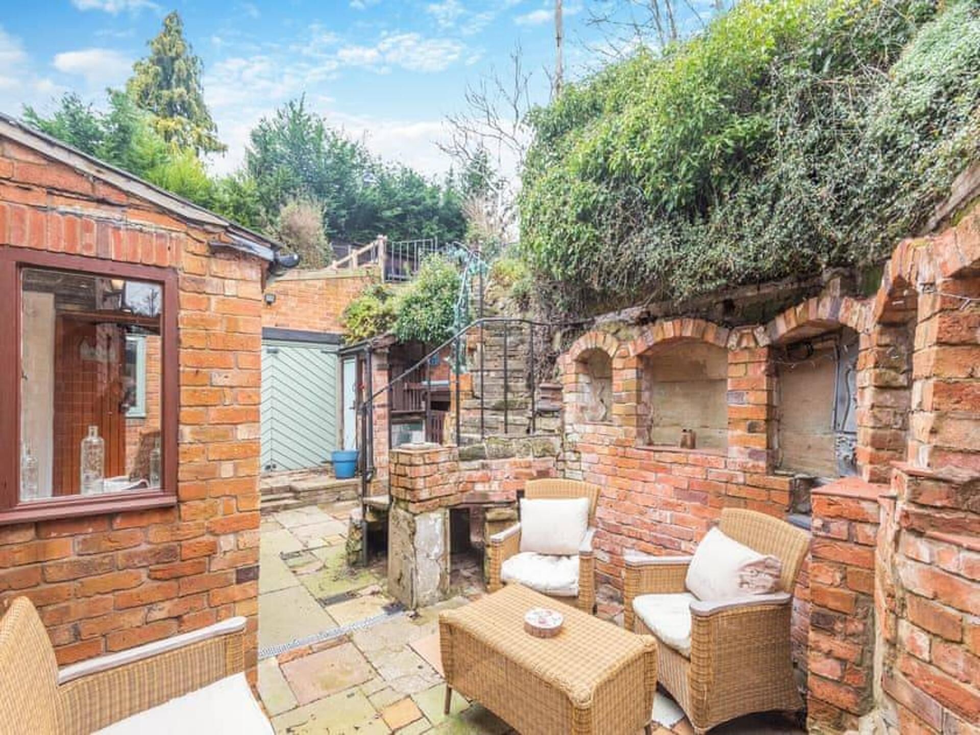 A brick building with a patio area featuring wicker furniture and a brick oven.