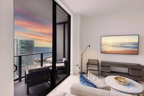A modern living room with a large window overlooking a cityscape and ocean view. - New! Stylish 1BR - Amenities & Pool (Miami)