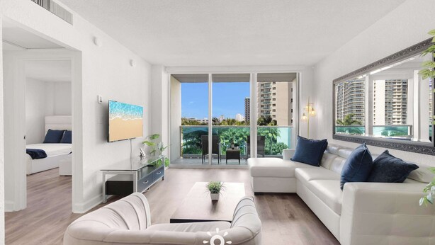 A modern living room with a sofa, coffee table, and a large window with a view of buildings and greenery. - Modern Hollywood Beach Escape - City Views (Hollywood)