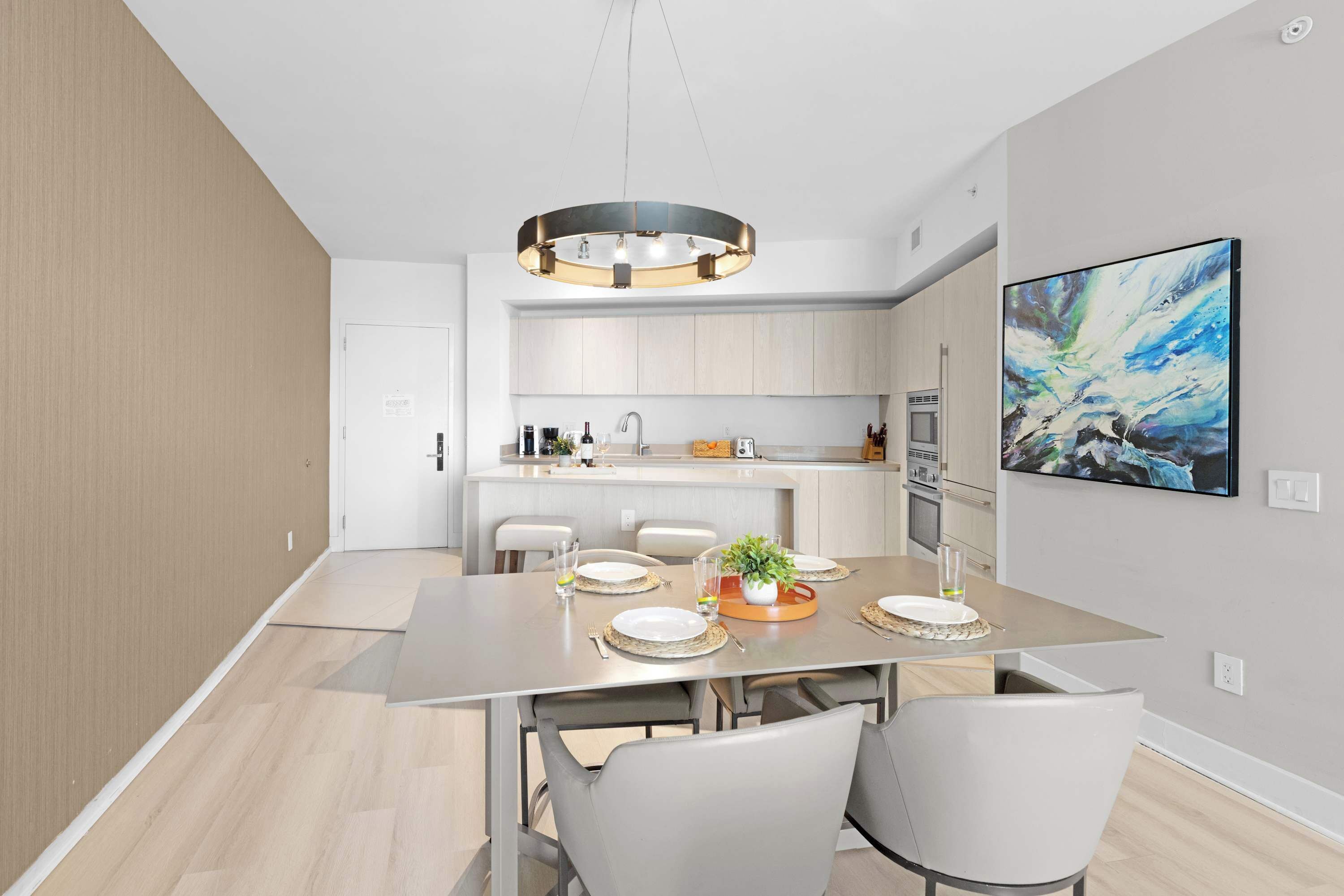 A modern kitchen with a central island, built-in appliances, and a dining area with a table set for four.